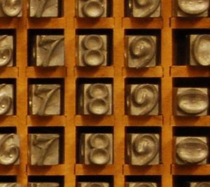 Closeup of the metal types used on an arithmetic type frame with raised numbers cast into their ends.