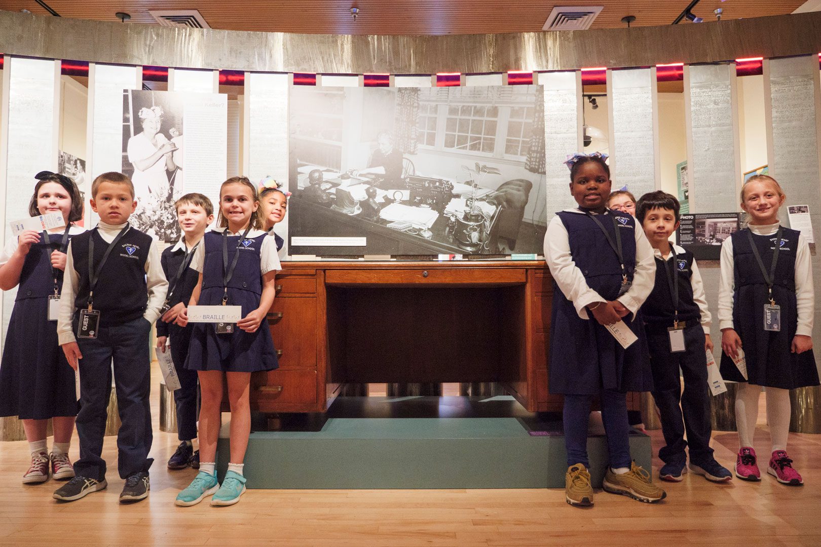 A group of students gathered around Helen Keller's desk in the APH Museum.