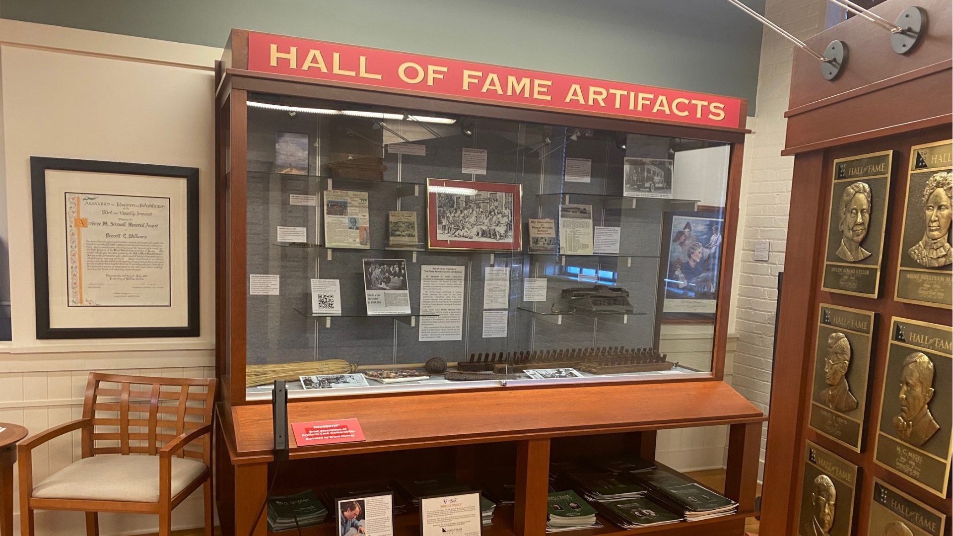 A large exhibit case made of wood and glass. Inside are various artifacts, documents, and photos.