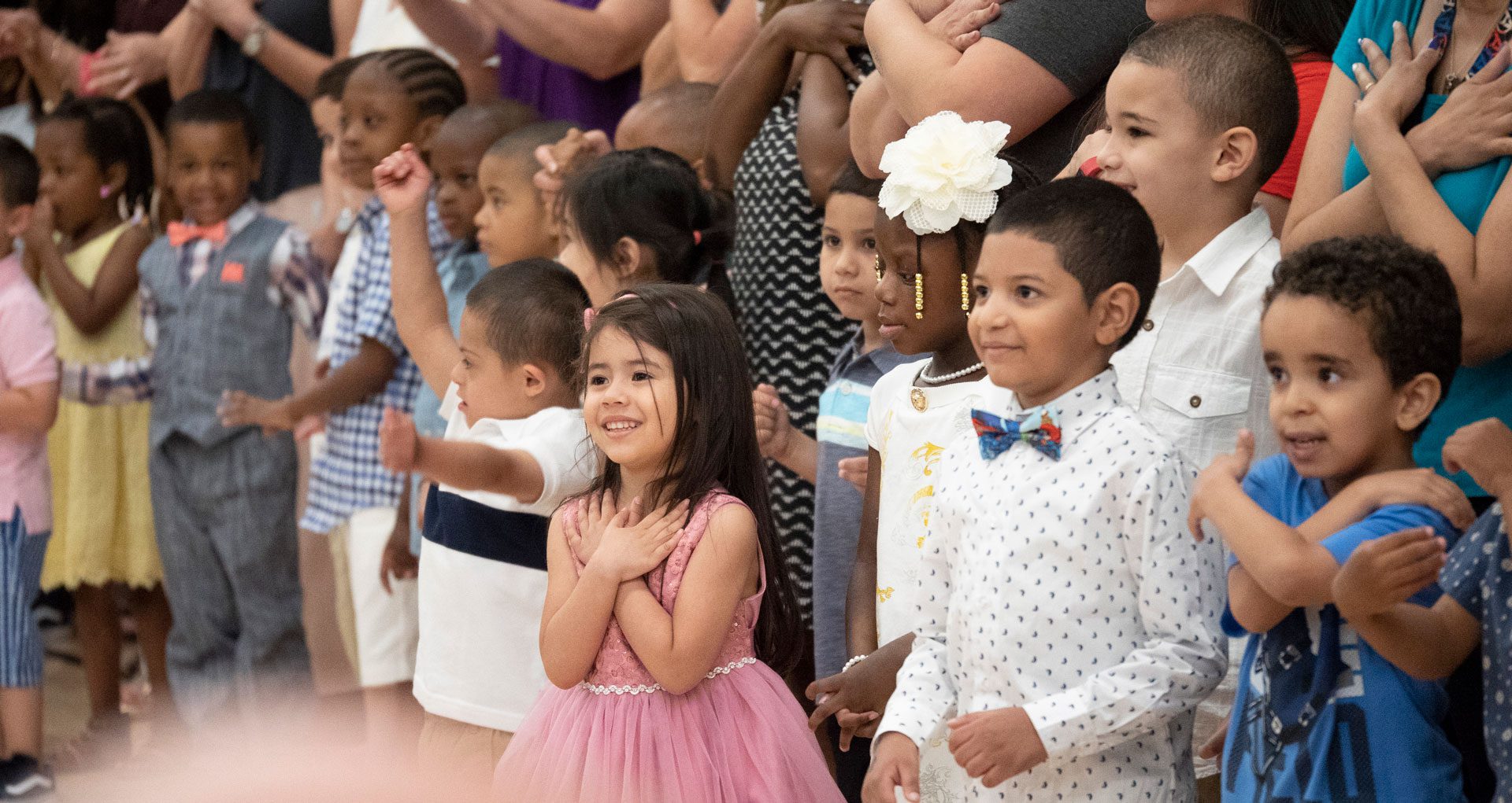 A diverse group of smiling elementary school students at an assembly.