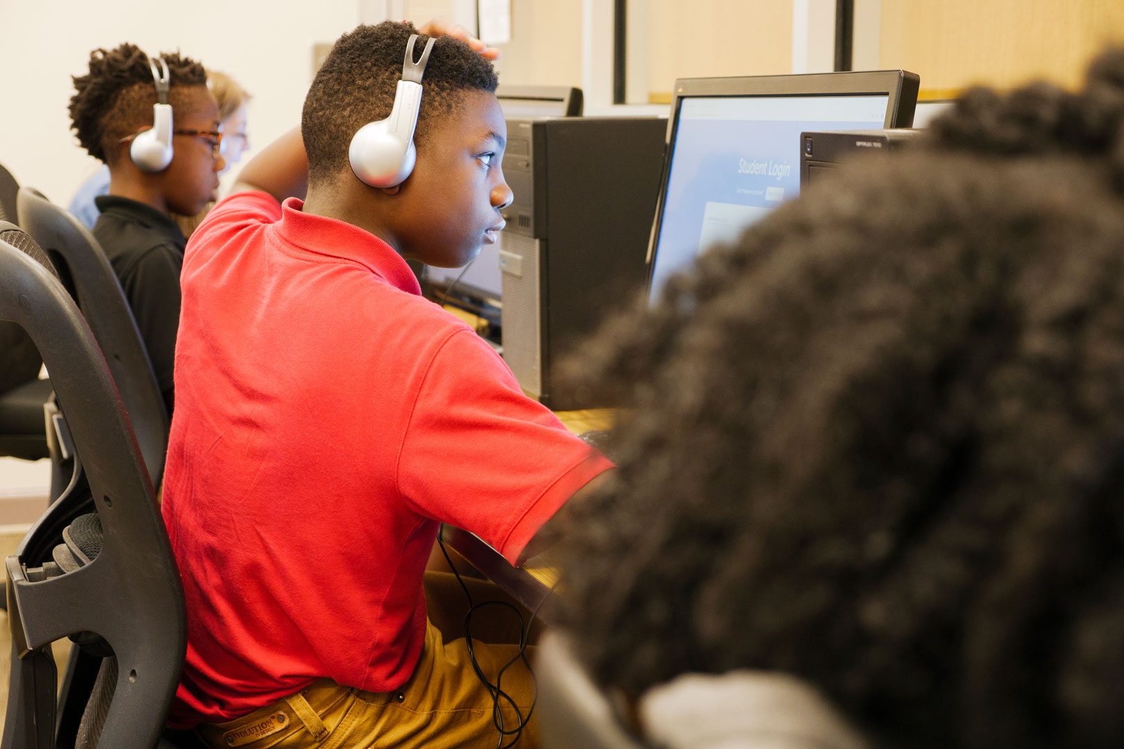 A student sitting at a computer wearing headphones.