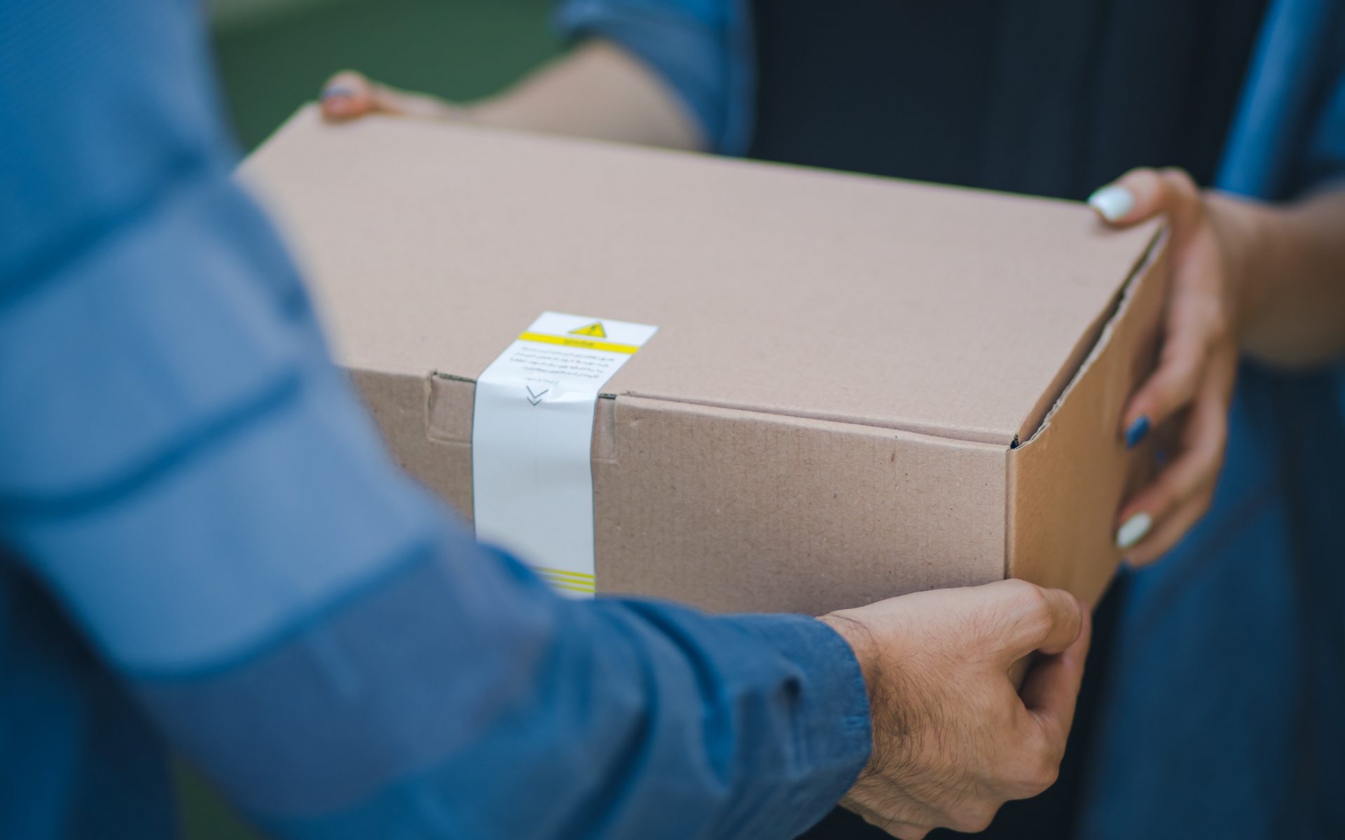 a brown cardboard package being handed from one person to another