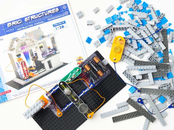 An aerial view of a light-emitting BRIC: Structures project built on a base plate. In the background is the BRIC: Structures box and an assortment of building blocks.