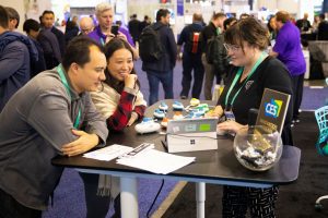 Two CES attendees watch an APH employee give a Code Jumper demonstration at the APH booth in the CES exhibit hall.