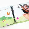 A child’s hand hovers above the page of the book wearing the included orange and black butterfly finger puppet. The pages of the book are illustrated with a green field and flowers and features print and braille text “And I showed him what he would become…”