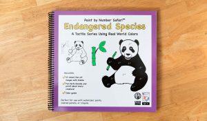 A spiral bound braille book with an illustration of a panda on the cover. It's holding a bamboo shoot. At the top it says "Paint by Numbers Safari TM Endangered Species"