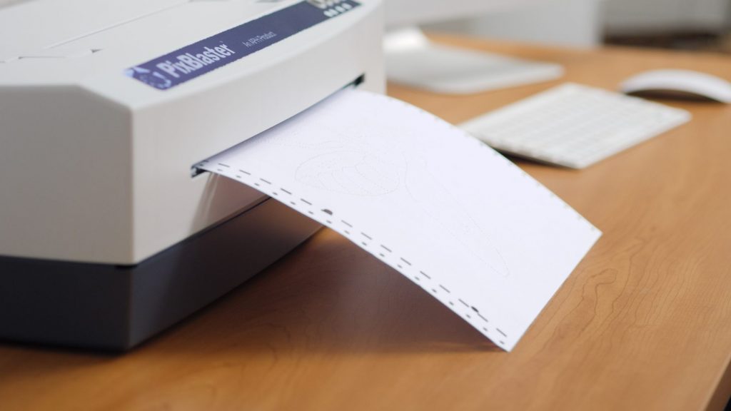 Close up of an embosser printing a tactile graphic on a desk.