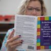 A seated woman reading a copy of Guidelines and Games for Teaching Efficient Braille Reading.