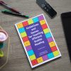 A copy of Guidelines and Games is resting on a dark gray table. To the left of the book is a container holding a Rubik’s Cube and Play-Doh, while two pens and an Apple TV remote are placed above the book, and an iPad is placed on the right side of the book.