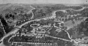 Aerial view of Rose Island Amusement Park showing the buildings in the park, the river beside the park, and the mountains behind the park