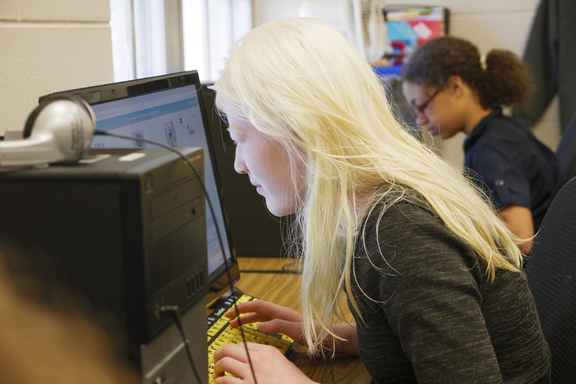 A teenager using a desktop computer in a computer lab.