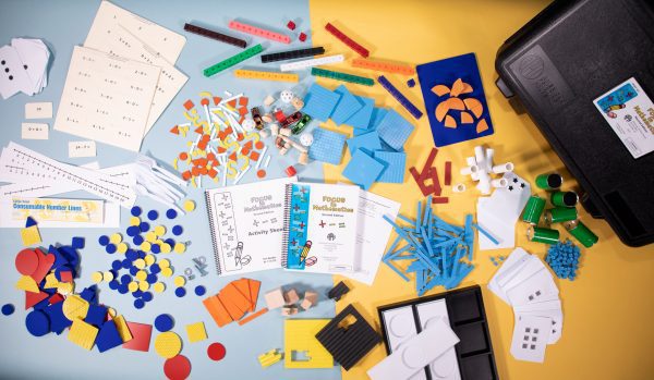 Bird's eye view of FOCUS in Mathematics Kit spread out to show the kits’ components including flash cards, guidebooks, colorful manipulatives, and more.