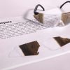 A pair of safety glasses containing the Hemianopsia insert sits on top of a printed page with information about the condition and an image of the insert laid flat.