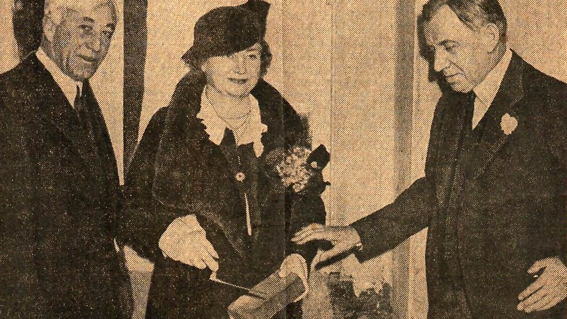 M.C. Migel, left, holds Helen Keller’s right hand and the trowel that they both hold over a cornerstone brick. Dr. John H. Finley, right, seems to move to hold the brick in Helen Keller’s left hand.
