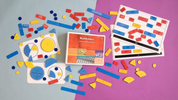 Bird's eye view of MathBuilders Unit 7 Kit: Fractions, Mixed Numbers, and Decimals spread out to show the kits’ components including tactile tokens, fraction circle trays, pie shaped fraction pieces, a guidebook, and more.