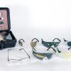All eight pairs of glasses included in the kit that mimic common eye conditions are laid out against a white background. To the left of the glasses is the box they come in with a visual guide to identify which inserts represent which conditions.