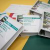 Large print Brigance binders loosely stacked on top of one another. The binders are resting on a yellow and green surface.