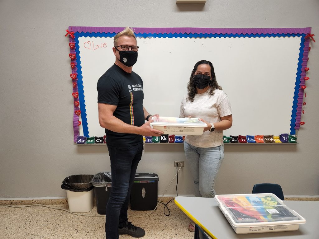 Jeff handing Spanish Legos Braille bricks to Diana Hernandez in school.