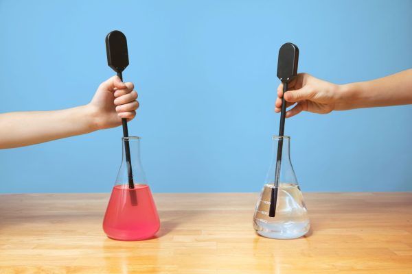 Two students each holding a SALS probe with the tip immersed in a flask filled with colored fluid on the left and clear fluid on the right.