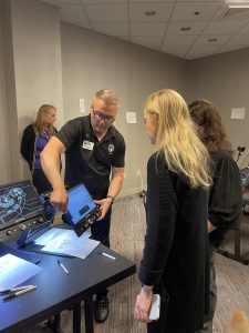 An APH employee shows two conference attendees how to use the Jupiter magnifier