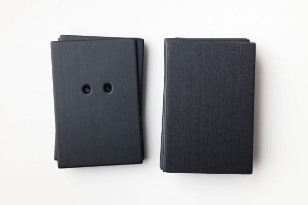 A package of black rectangle-shaped cards (10 undrilled and 5 two-hole drilled)