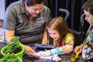 CATT trainer using a Juno magnifier to look at plants with a young girl.