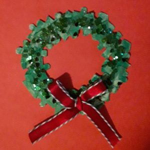 Green craft wreath made out of puzzle pieces with a red bow at the bottom.