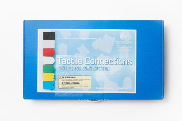 A fluted cardboard carrying box with handle for the APH’s Tactile Connections: Symbols for Communication. A Small Parts Choking Hazard label appears on the box in both print and braille, as well as the title of the product.