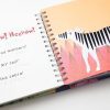 The book is opened to show two pages. On the left-hand page in large pink text reads, “Heehaw! Heehaw!.” Underneath that in large text reads, ““What bad manners! That’s MY tail!” says the zebra!” Under each line of large print text is the braille translation. On the right-hand page is a white and black striped zebra on top of a peach and pink background. The zebra’s tail is made from rope and a small white brush.