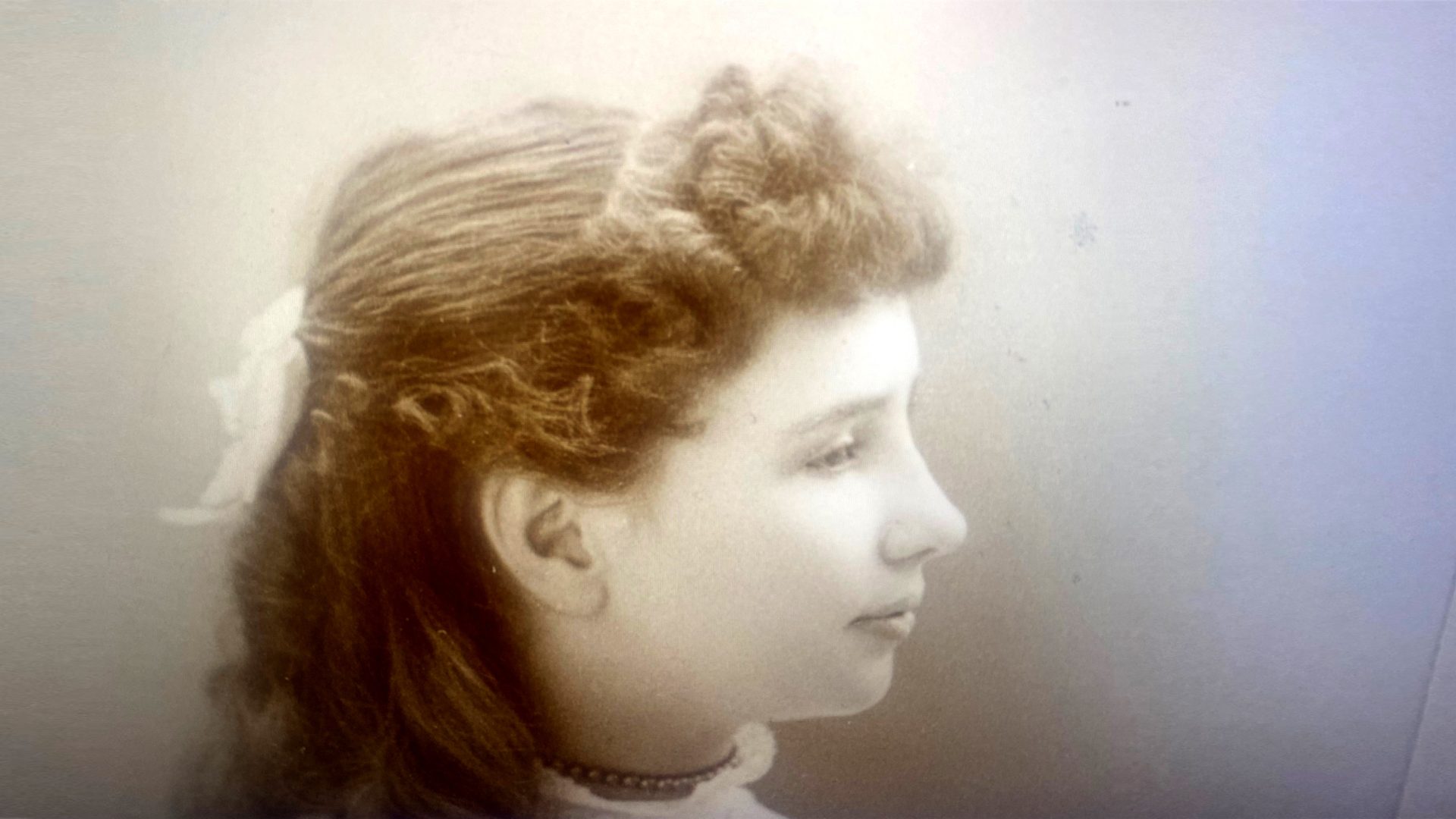Studio photo of a young girl, about 10. Her hair has been styled with fluffy bangs and long curls.