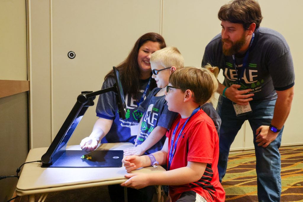 Two CATT Trainers looking over students viewing plants under the Jupiter Video Magnifier.