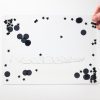 Zoomed out image of a black swirly mat over a white background. Black stars and circles are show inside the mat.