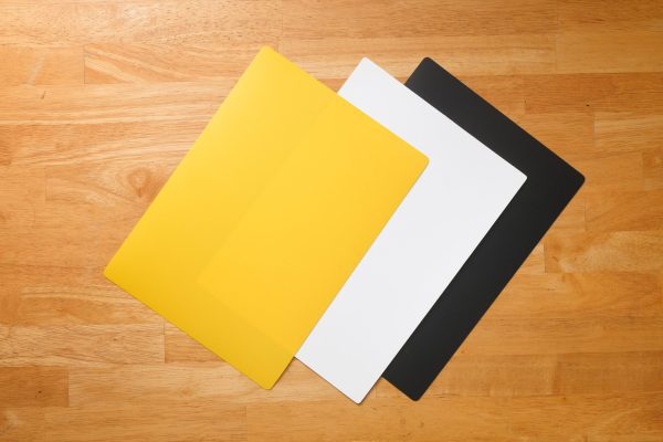 Tabletop mat pack on top of a wooden surface. The color and order of the mats are yellow, white, and black.