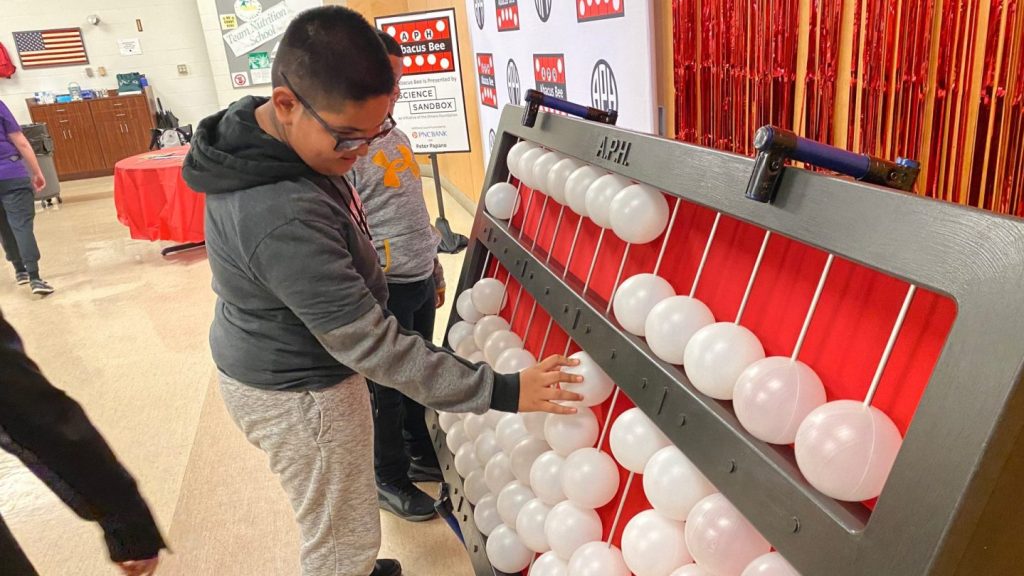 A young boy moves the beads on a giant Cranmer abacus.