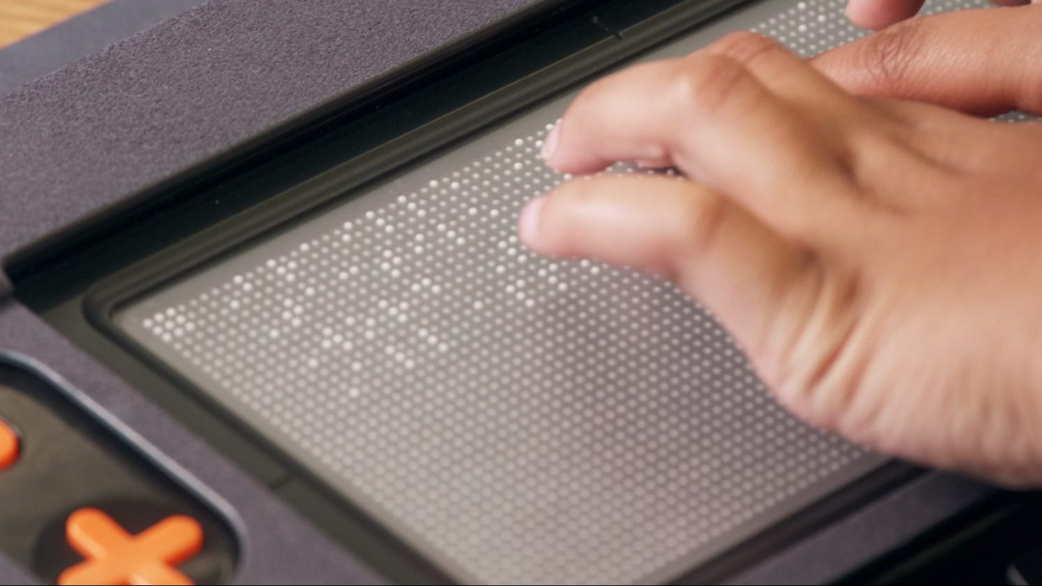 Hands reading multiple lines of braille on a 10 line refreshable braille display.