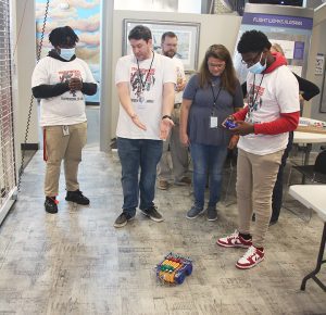 One student controls an RC Snap Rover while several other students and instructors watch and chat with each other.