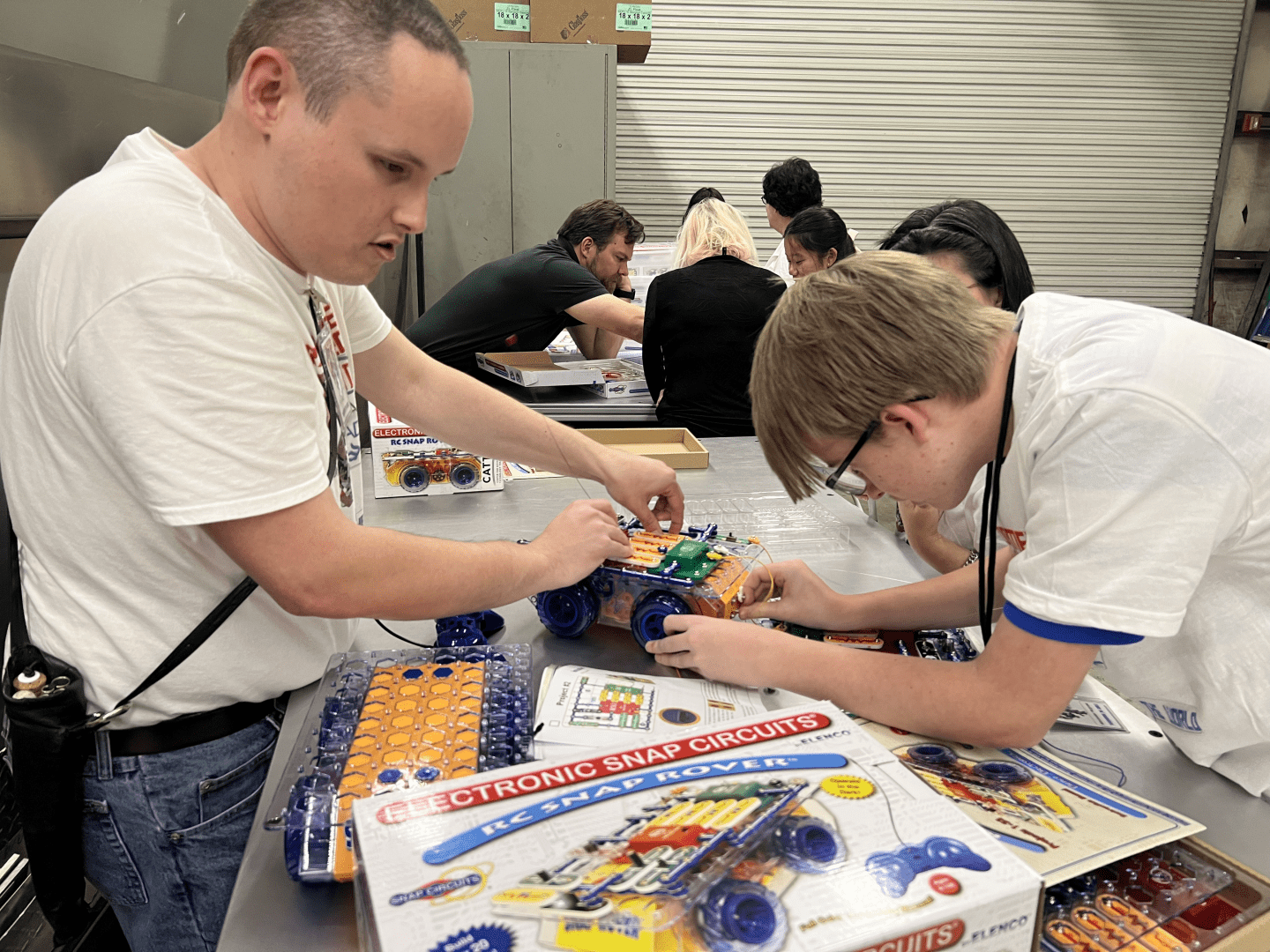 An adult helps a teenager put together an RC Snap Rover.