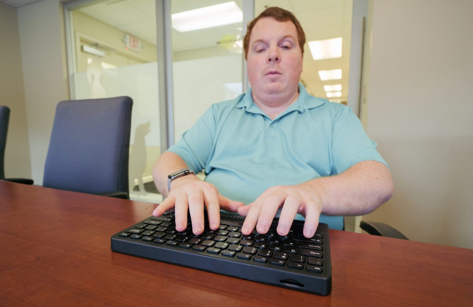 A man types on a Mantis Q40 in an office.