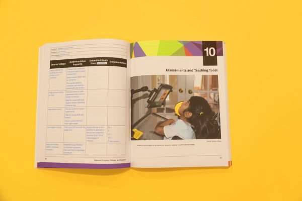 Sensing and Learning on a yellow background opened to pages 96 and 97. Page 96 shows a 4x5 chart with the following columns: Learner’s Steps, Accommodation Supports, Embedded Goals Zone: Function, and Documentation. Page 97 is opened to Chapter 10 – Assessments and Teaching Tools, which shows an image of a young learner turning pages on her electronic book by tapping a switch to her cheek