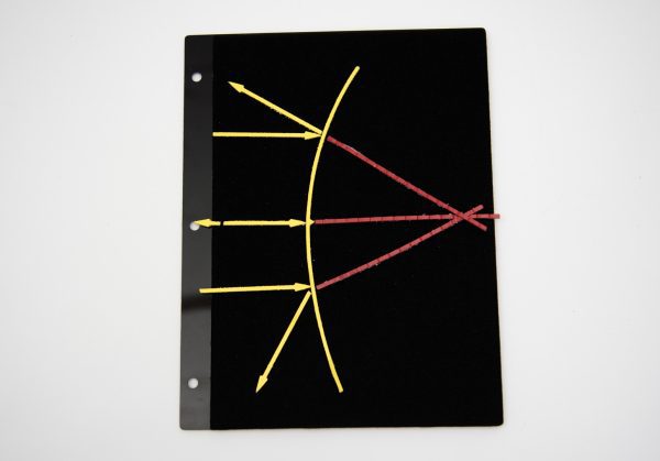 A diagram representing refraction made from yellow and red stick-on pieces that rest on top of a black storage panel.