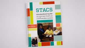 Guidebook—Title is STACS: Standardized Tactile Communication Symbols by Ellen Trief, Ph.D. Images show learners using the communication symbol cards to choose between yes or no, and to choose music or circle time.