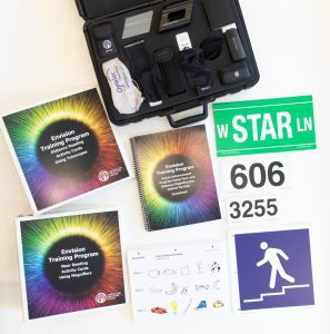 Envision Kit with Optical Aids opened to show training curriculum, activity cards, signage, and the carrying case which houses optical arrays
