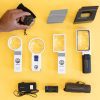 Optical aids including magnifiers and magnifier holders are shown out of box over a yellow background. In the top left-hand corner, a hand is holding a circular magnifier.