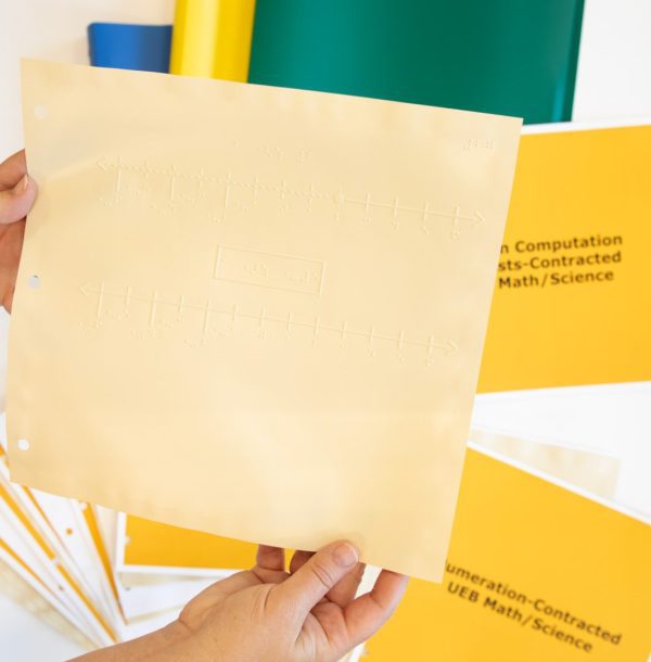 Close-up of a tactile sheet which features two number-lines, graphed points, and contracted braille labels.