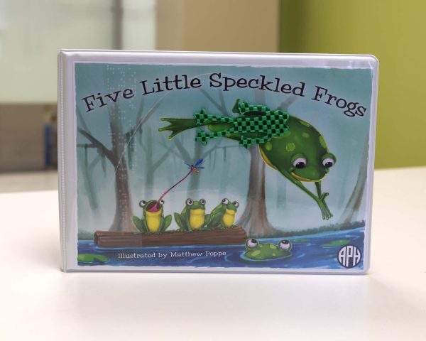 Five Little Speckled Frogs binder cover with an illustration of three frogs on a log floating in the water with one catching a flying insect with its tongue. A fourth frog is floating in the water with just the top of his head and eyes showing, while a fifth frog is diving into the water. A flat green tactile frog shape is stuck over part of the diving frog's body.