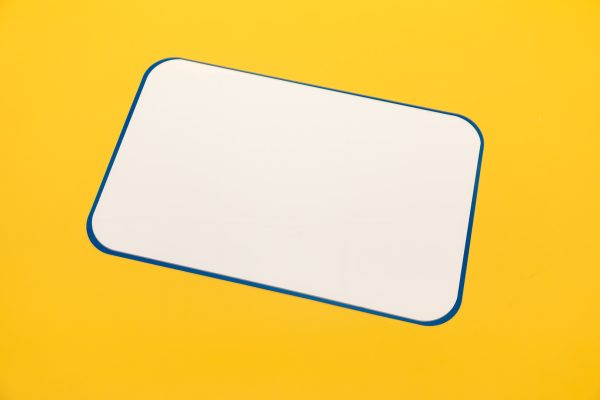 A white magnetic dry erase board included in the Sports Courts kit. The edges of the board are blue, and it sits against a yellow background.