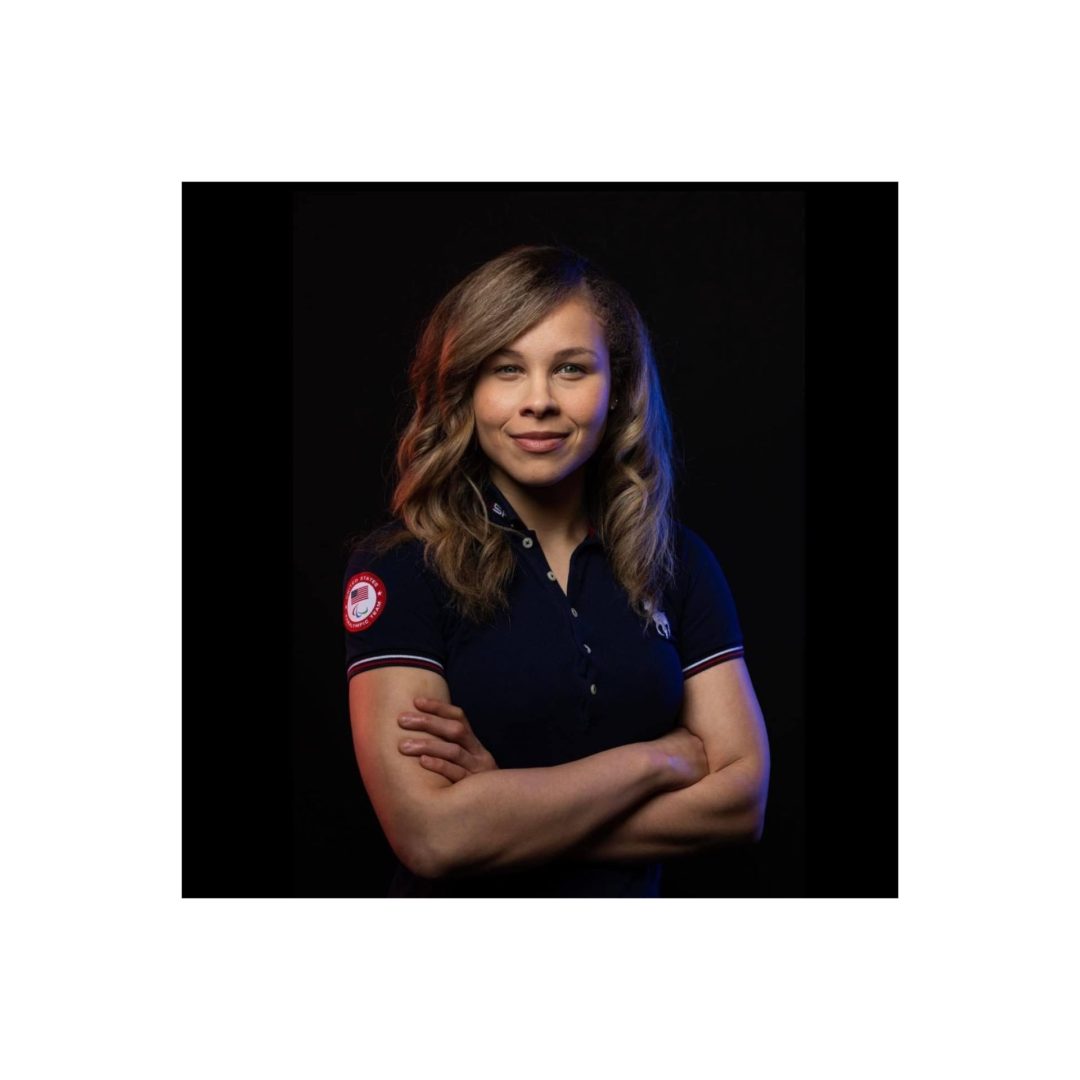 Amanda Dennis poses with her arms crossed while wearing a Team USA Paralympic branded shirt.