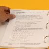 A hand holding one corner of a page of an open Rules of UEB large print binder. The information on the page pertains to differences between single and double quotation marks.