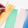 A hand separating one yellow dashed line path strip from the perforated set. Next to the dashed strips are dotted, greater-than, and railroad line path strips in green, clear, and blue.