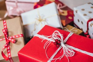 A stack of presents wrapped in red, white, brown, and polka-dotted paper. Many of the packages have festive bows tied around them.